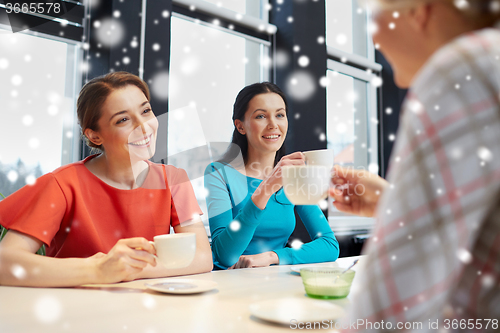 Image of happy young women drinking tea or coffee at cafe