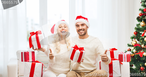 Image of happy couple with christmas gifts and thumbs up