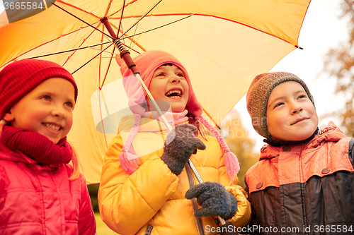 Image of happy children with umbrella in autumn park