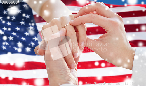 Image of close up of lesbian couple hands with wedding ring