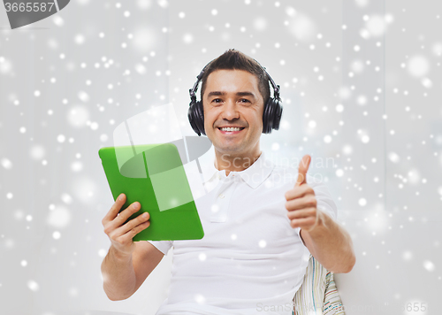 Image of smiling man with tablet pc and headphones at home