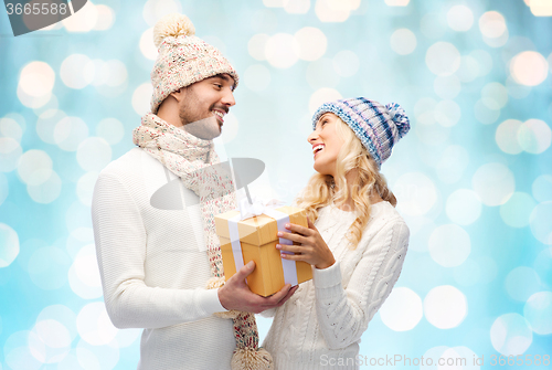 Image of smiling couple in winter clothes with gift box