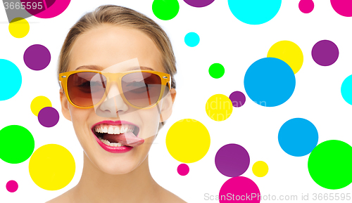 Image of happy young woman in sunglasses showing tongue