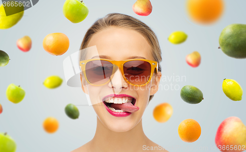 Image of happy young woman in sunglasses showing tongue