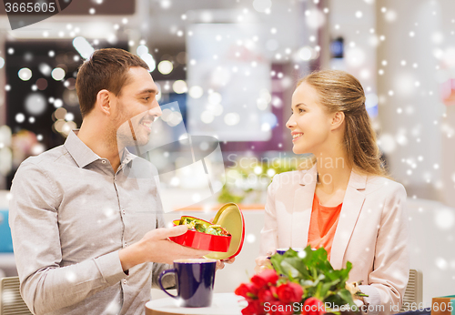 Image of happy couple with chocolate box and roses in mall