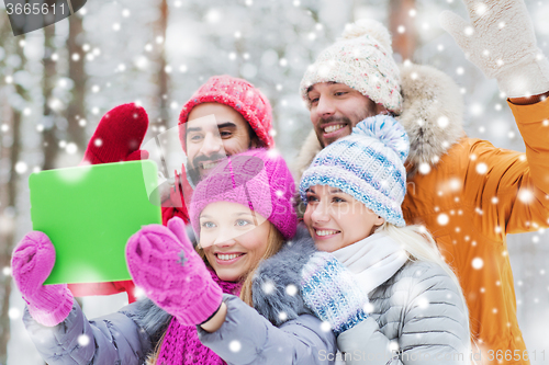 Image of smiling friends with tablet pc in winter forest