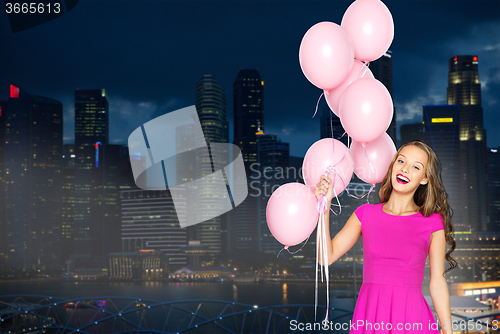 Image of happy young woman with balloons over night city