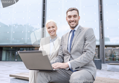 Image of smiling businesspeople with laptop outdoors