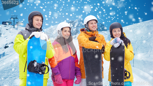 Image of happy friends with snowboards over mountains