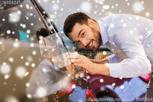 Image of happy man touching car in auto show or salon