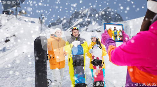 Image of happy friends with snowboards and tablet pc