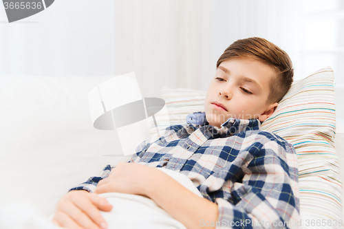 Image of ill boy with flu lying in bed at home