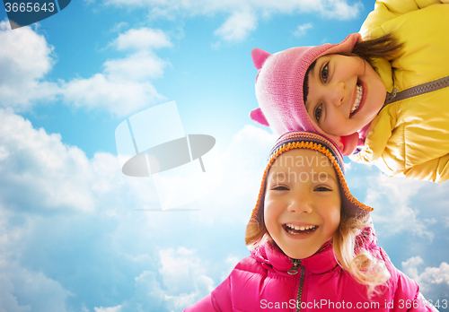 Image of happy little girls faces over blue sky