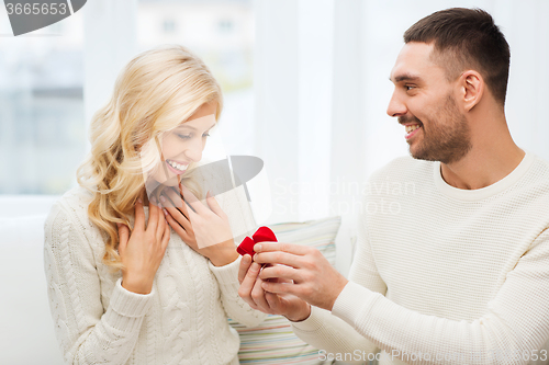 Image of happy man giving engagement ring to woman at home