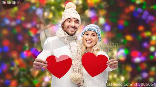 Image of smiling couple in winter clothes with red hearts