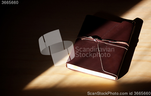 Image of closed brown leather diary with flap and lacing