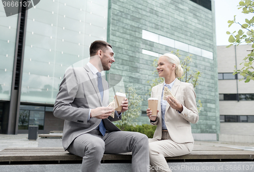 Image of smiling businessmen with paper cups outdoors