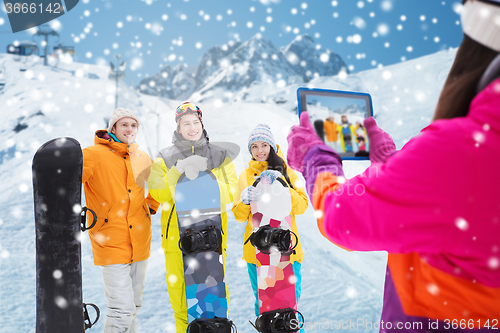 Image of happy friends with snowboards and tablet pc