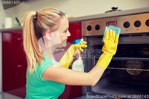 Image of happy woman cleaning cooker at home kitchen