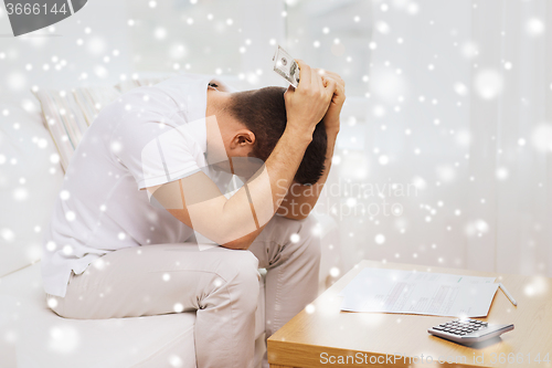 Image of man with money and calculator at home