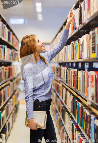 Image of happy student girl or woman with book in library