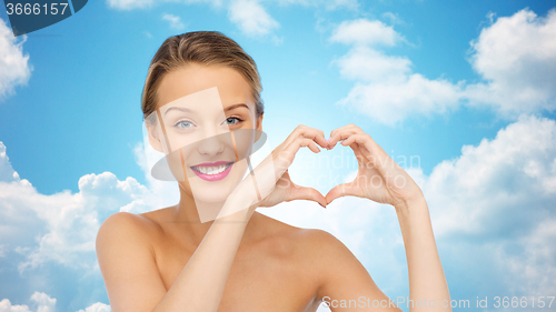 Image of smiling young woman showing heart shape hand sign