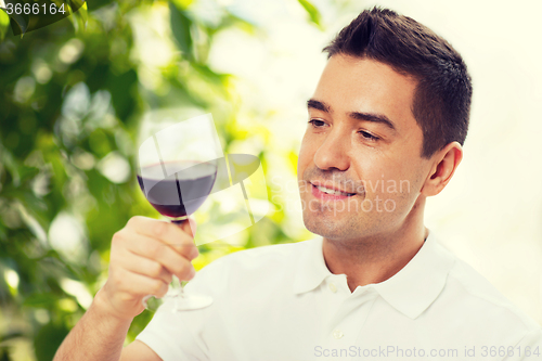 Image of happy man drinking red wine from glass