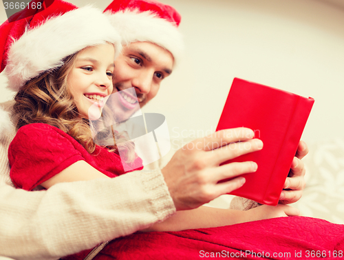 Image of smiling father and daughter reading book