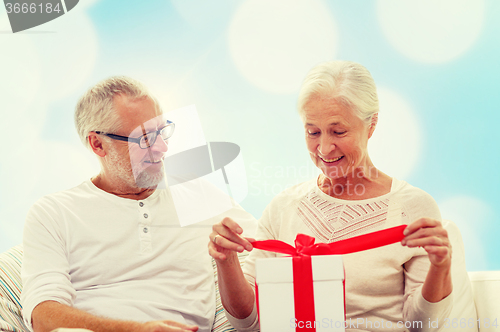 Image of happy senior couple with gift box at home