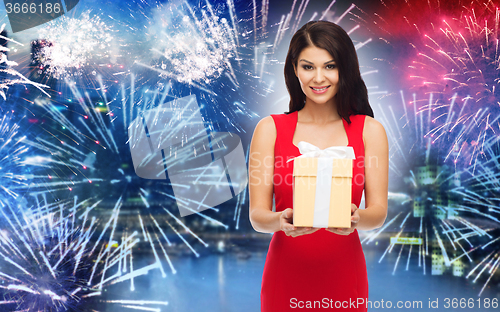 Image of happy woman in red dress with gift over firework