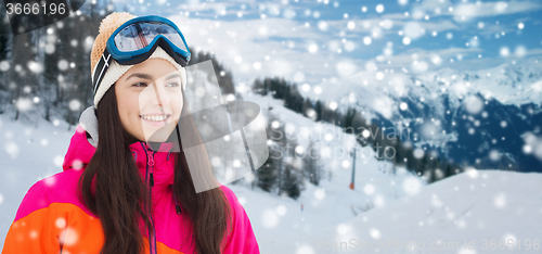 Image of happy young woman in ski goggles over mountains