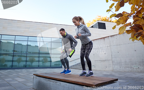 Image of man and woman exercising on bench outdoors