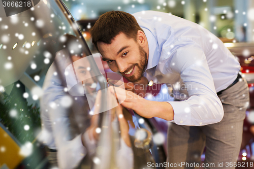 Image of happy man touching car in auto show or salon