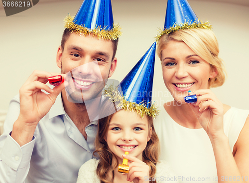 Image of smiling family in blue hats blowing favor horns