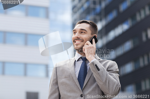Image of smiling businessman with smartphone outdoors