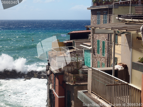 Image of Riomaggiore Cinque Terre Italy waves breaking against historic h