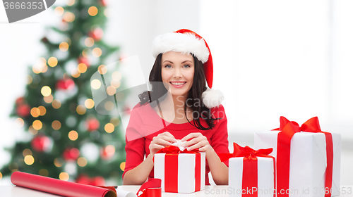 Image of woman in santa helper hat with many gift boxes