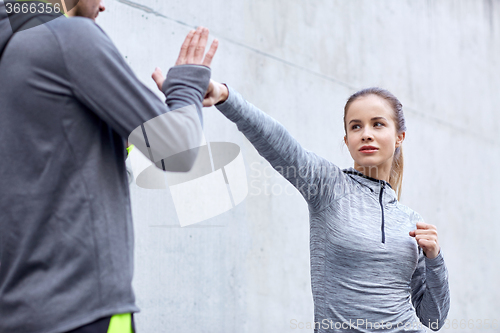 Image of woman with coach working out strike outdoors