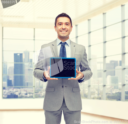 Image of happy businessman in suit showing tablet pc screen
