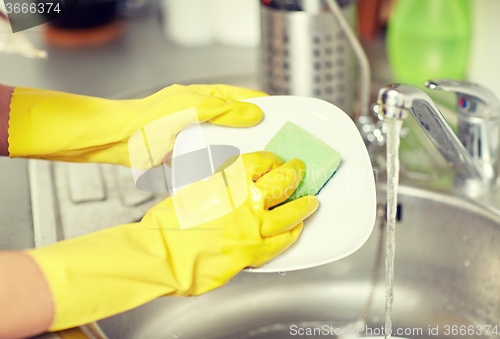 Image of close up of woman hands washing dishes in kitchen