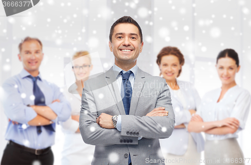 Image of happy businessman over team at office