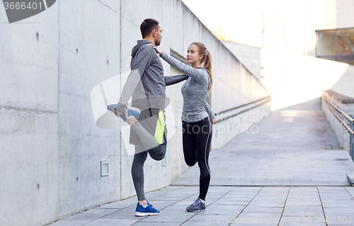 Image of smiling couple stretching leg outdoors