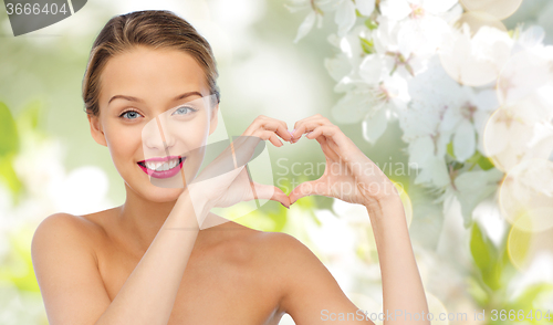 Image of smiling young woman showing heart shape hand sign