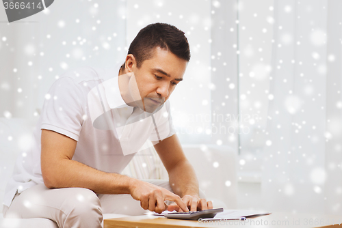 Image of man with papers and calculator at home