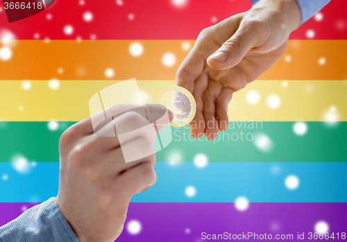 Image of close up of male gay couple hands giving condom