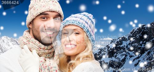 Image of smiling couple in winter clothes over mountains