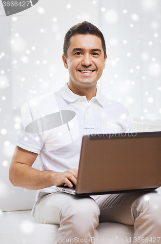 Image of happy man working with laptop computer at home