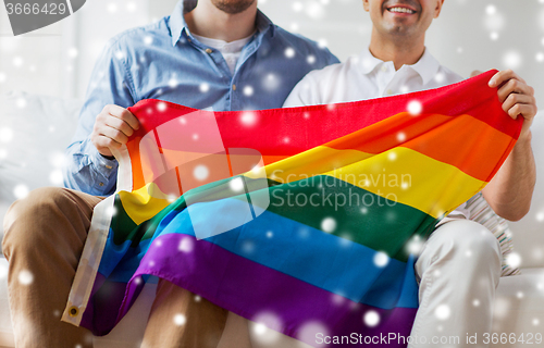 Image of close up of male gay couple holding rainbow flag