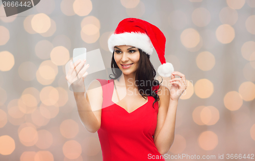 Image of woman in santa hat taking selfie by smartphone