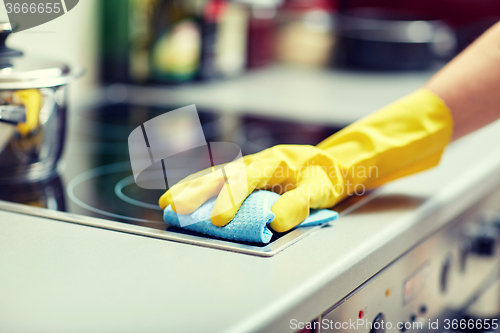 Image of close up of woman cleaning cooker at home kitchen